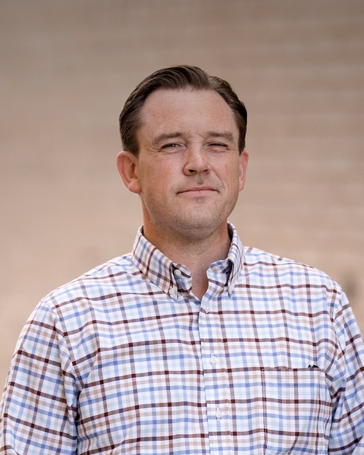 Dave Manley, chest-up portrait against a warm wall